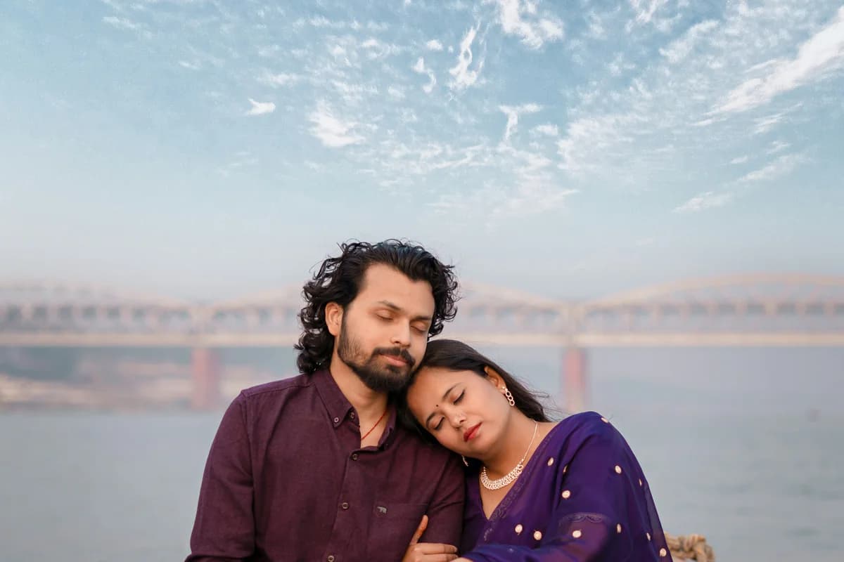 Two people in Indian attire sitting close together beside the water