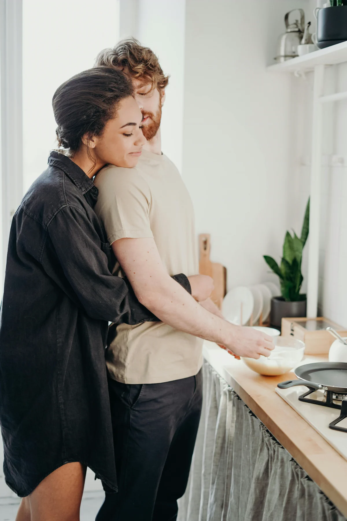 A couple embraces while preparing food in a kitchen