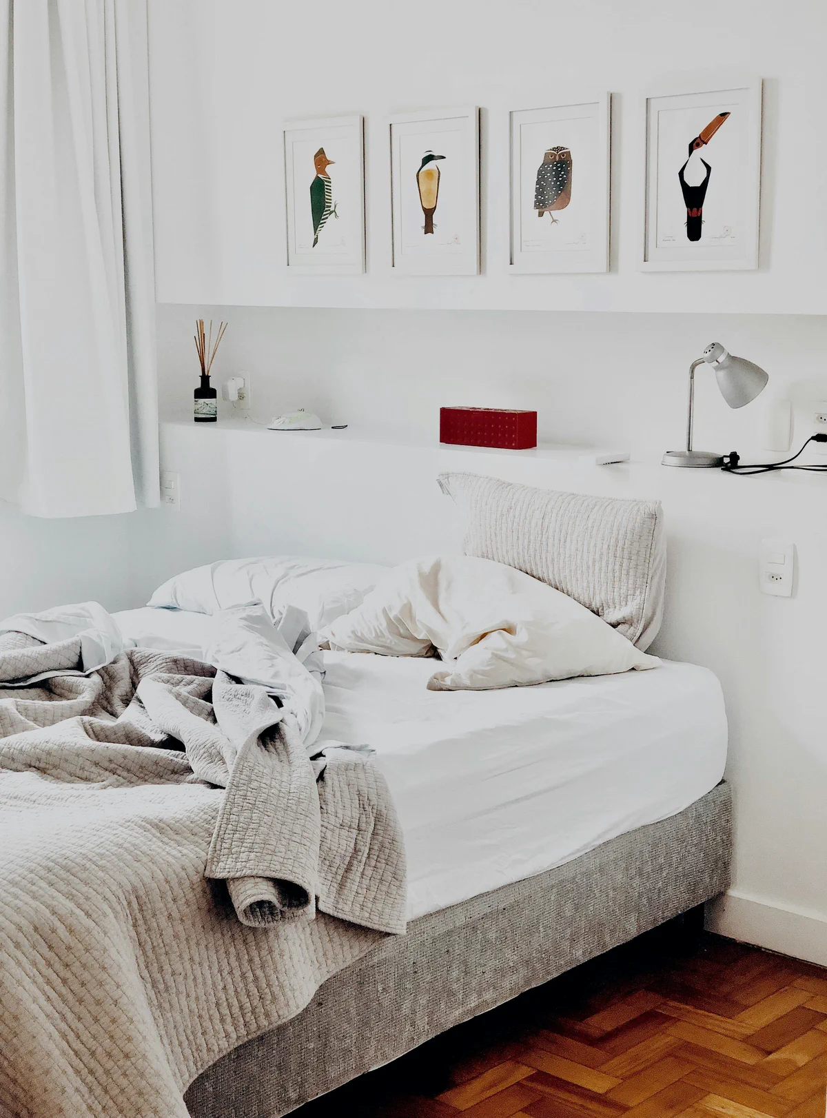 An unmade bed in a bright white bedroom