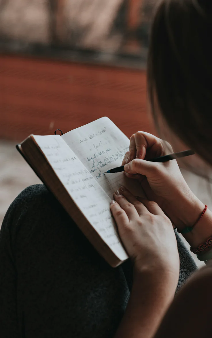 A person writing a guided reflection in a notebook
