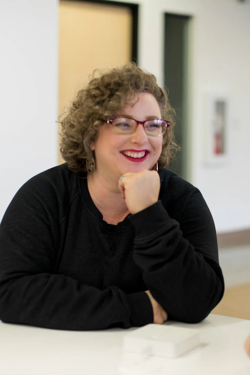 A person smiling across a table during a conversation
