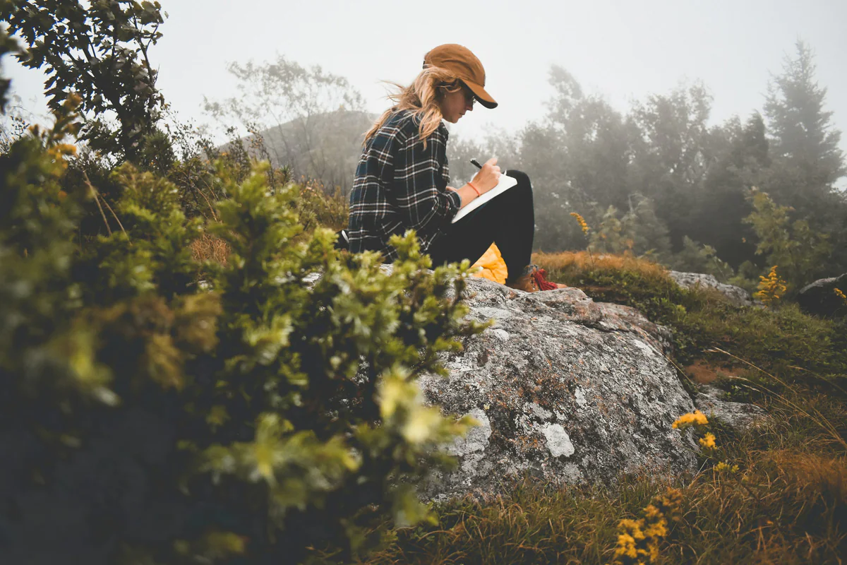 Woman writing in a notebook on a misty hillside