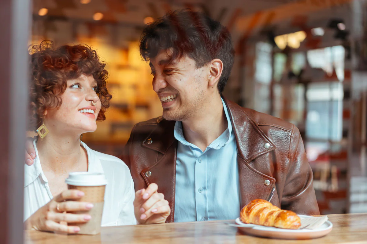 Two people laughing together over coffee in a cafe