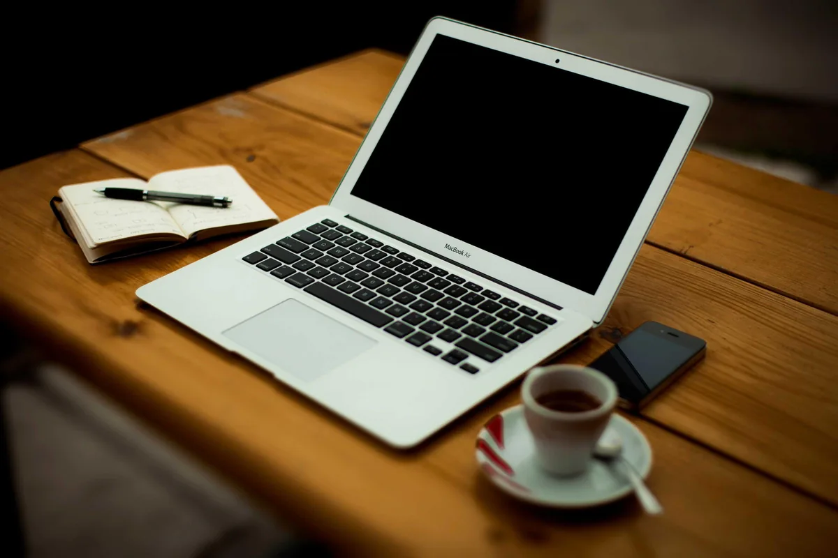 A person working on a laptop beside a coffee cup