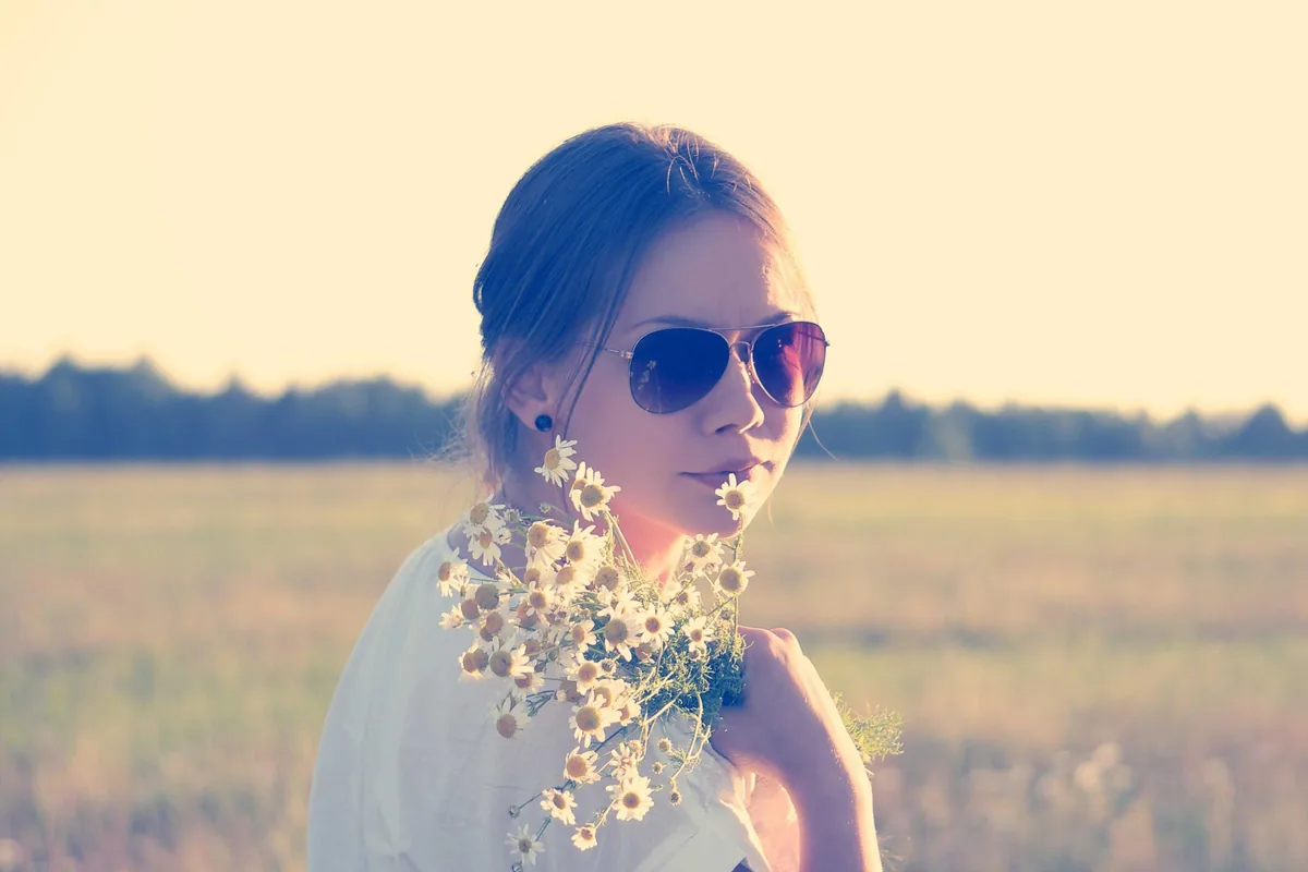 A woman holding flowers in a bright summer field