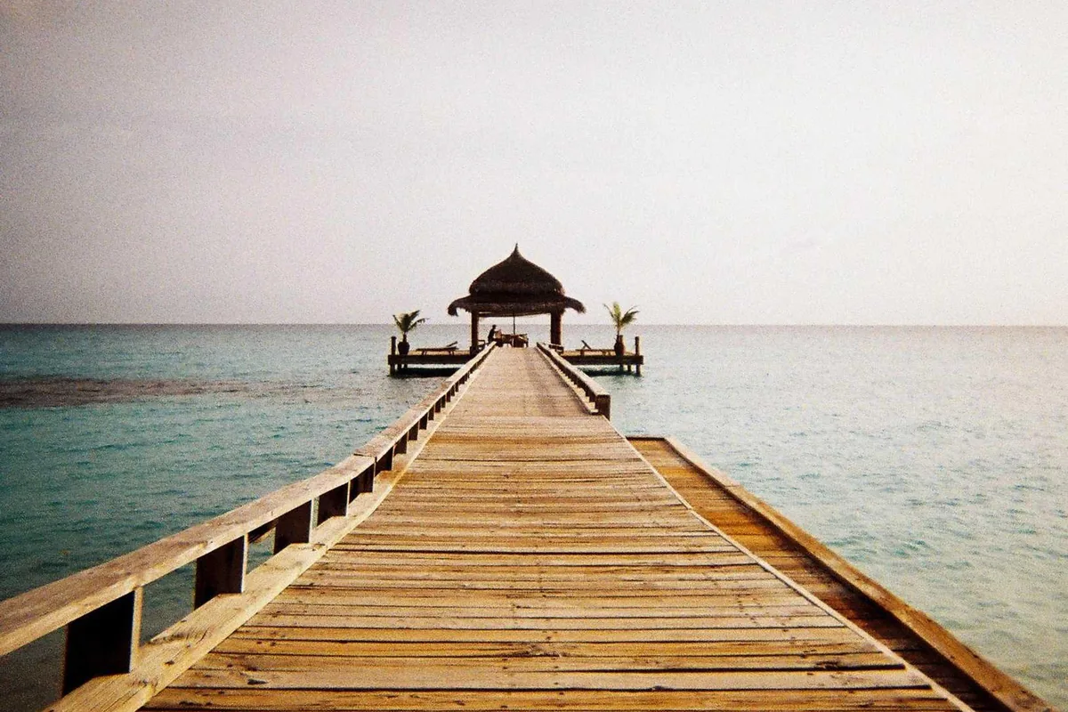 A wooden pier leading into calm water at dusk