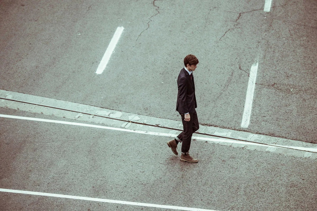 A young man crossing a city street, seen from above