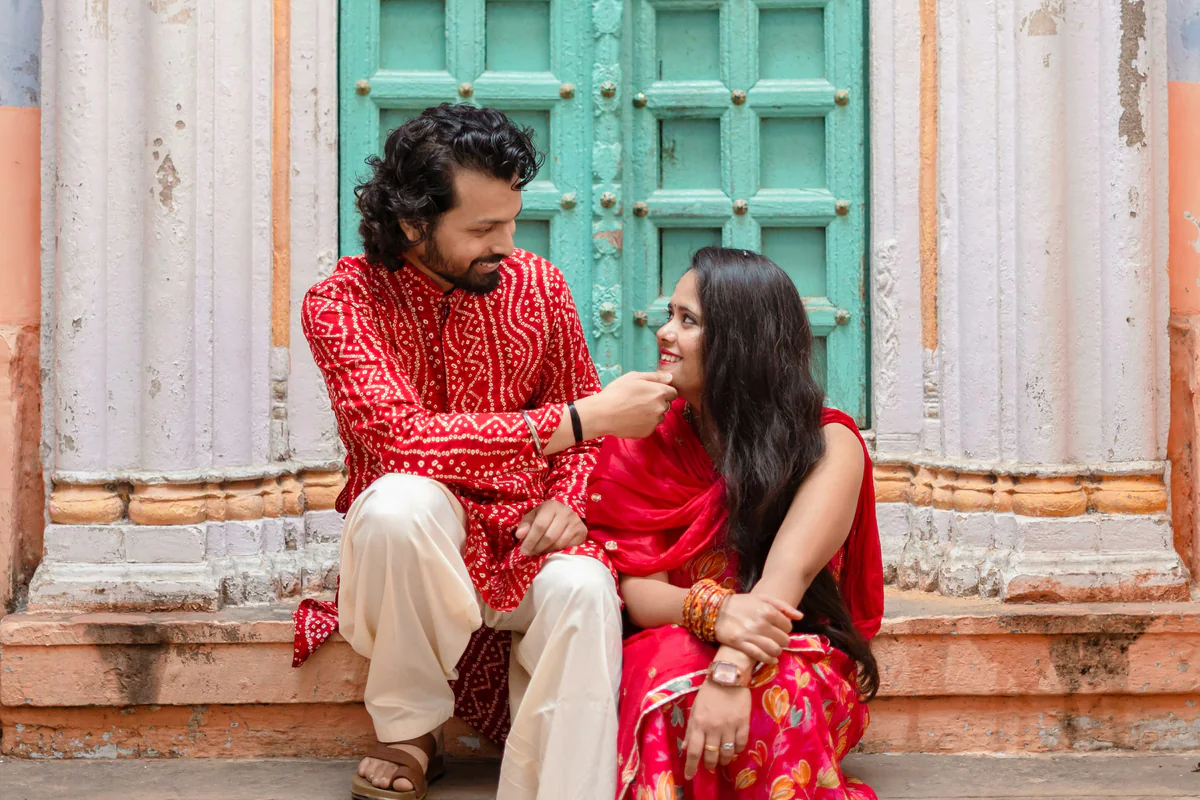 Two people in Indian attire sitting together and looking at each other